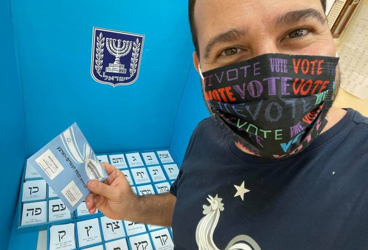 Élections israéliennes de mars 2021, un jeune homme dans l'isoloir de vote avec les nombreux bulletins de vote