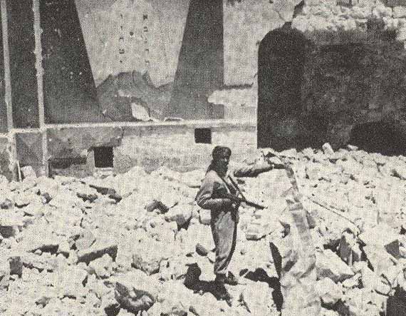 Un soldat jordanien sur les ruines de la synagogue Hurva à Jerusalem (1949), durant l'occupation jordanienne. Tout le quartier juif de la vieille ville et ses 52 synagogues ont été détruits.